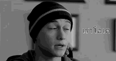 a young man wearing a beanie is talking on a cell phone .