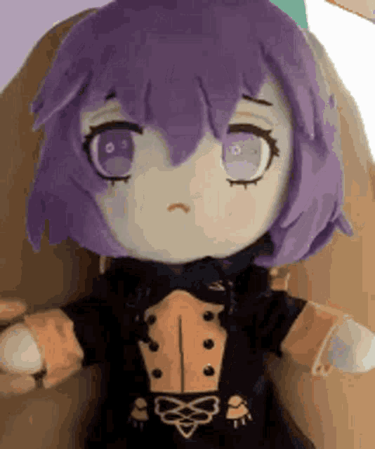 a stuffed doll with purple hair and blue eyes is being held in a person 's hand .