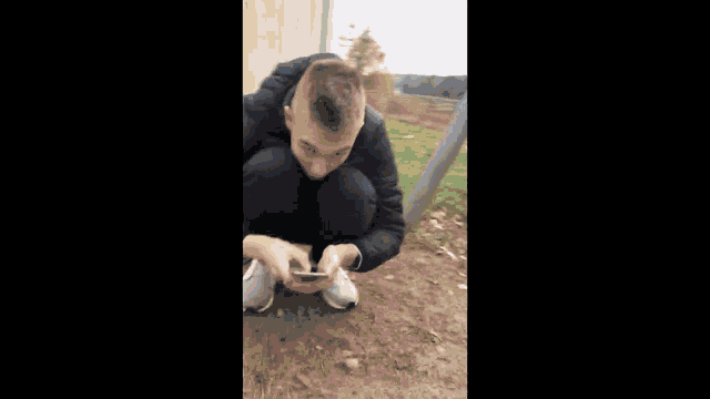 a person in a black jacket is squatting in the dirt .