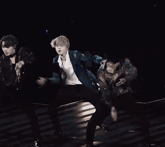 a group of men are dancing on a stage with a light shining on them .
