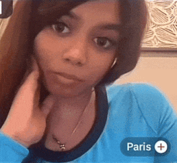 a woman in a blue shirt is taking a selfie with a paris icon in the corner .