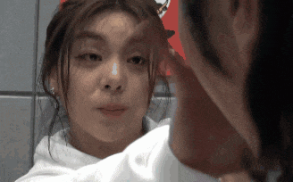 a woman looks at her face in the mirror