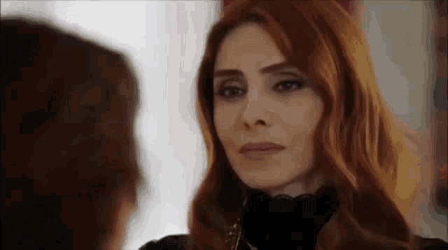 a woman with red hair is looking at herself in the mirror .