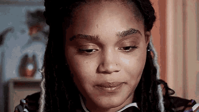 a close up of a woman 's face with dreadlocks making a funny face .