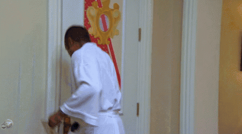 a man in a white robe stands in a doorway