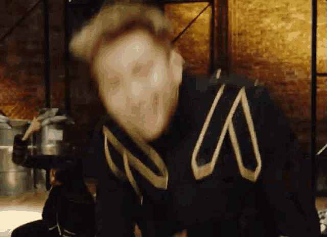 a man wearing a black and gold jacket with the letter s on it