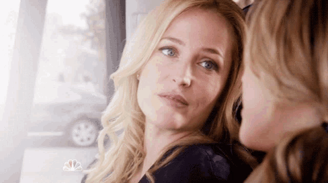 two women are looking at each other with a nbc logo in the upper right corner