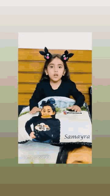 a little girl is holding a pillow with a picture of her on it .