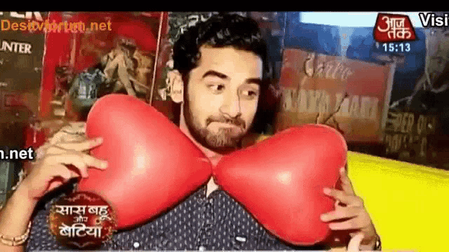 a man is holding two red heart shaped balloons .
