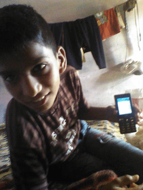 a young boy is holding a cell phone and wearing a shirt that says ' i love you ' on the front
