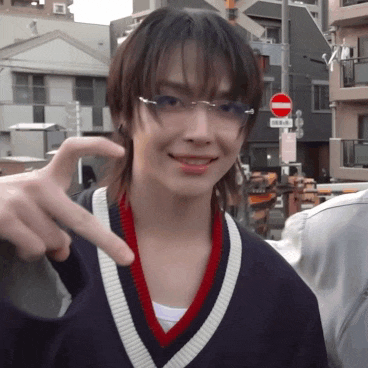 a young woman wearing glasses and a sweater is giving a peace sign