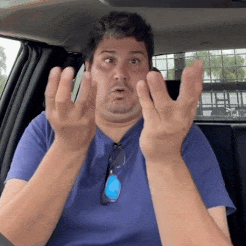 a man sitting in a car with his hands up