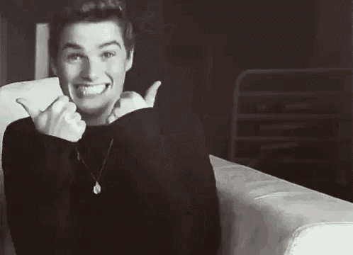 a young man is sitting on a couch and smiling .