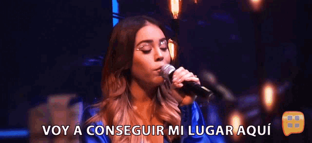 a woman singing into a microphone with the words voy a conseguir mi lugar aqui behind her