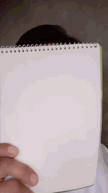 a person covering their face with a notebook