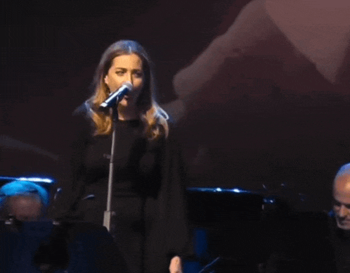 a woman is singing into a microphone on stage