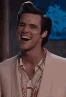 a man in a suit and hawaiian shirt is laughing and smiling .