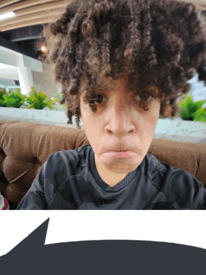 a person with curly hair making a sad face while sitting on a couch
