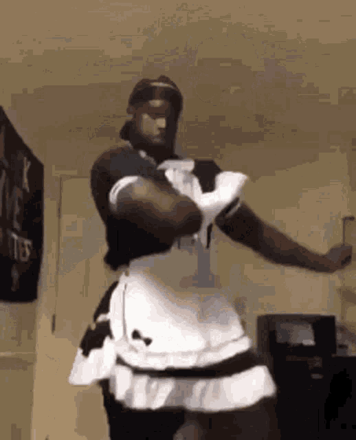 a man is wearing a maid dress and gloves and dancing in a room .
