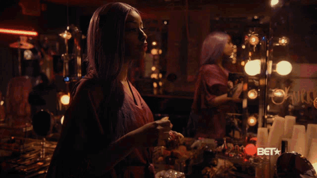 a woman with purple hair is standing in front of a mirror with bet written on the bottom