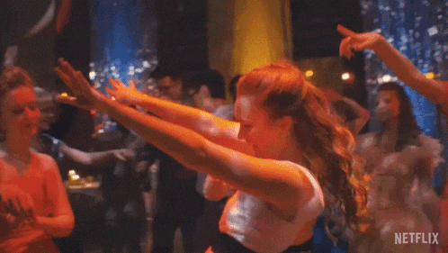 a woman is dancing on a dance floor with her arms in the air in a club .