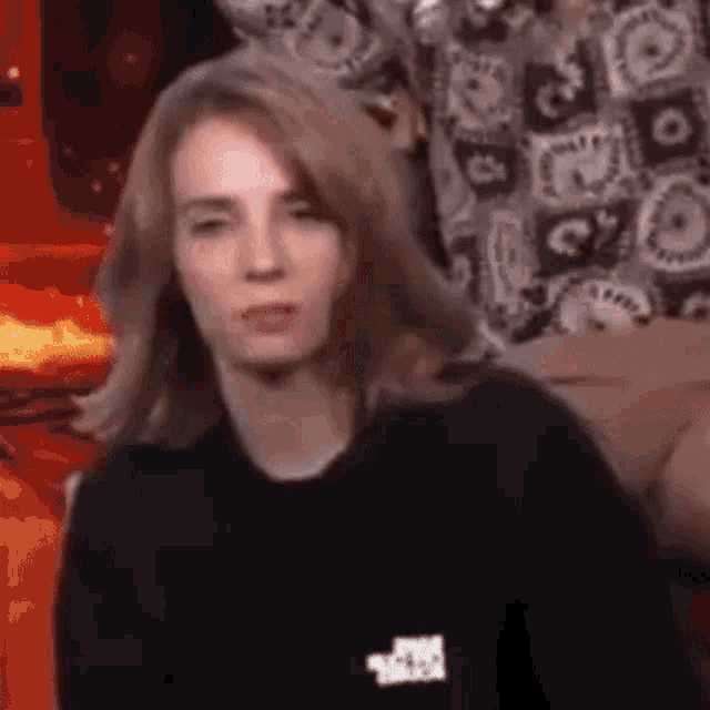 a woman wearing a black sweater is making a funny face .