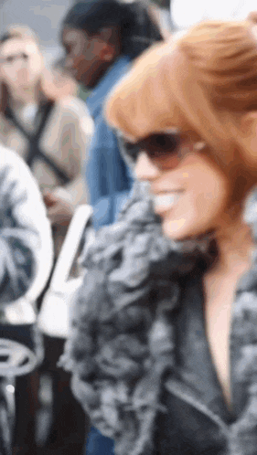 a woman with red hair wearing sunglasses and a black jacket