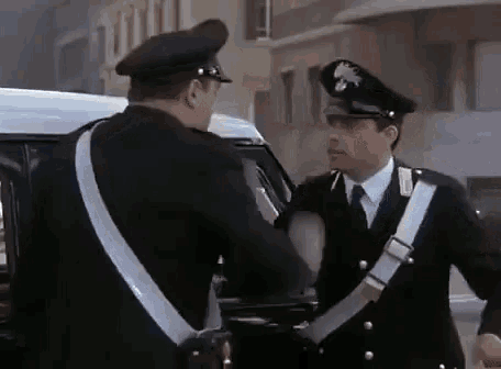 two police officers are standing next to each other talking to each other .
