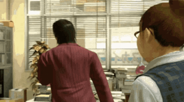 a man and a woman are standing in front of a window in an office