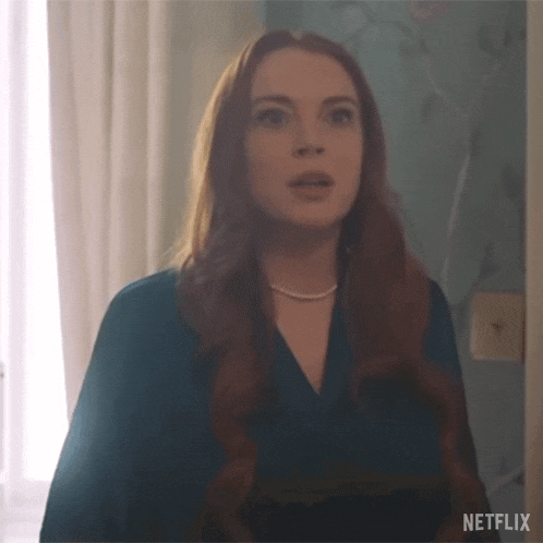 a woman with long red hair and a pearl necklace is standing in a room .