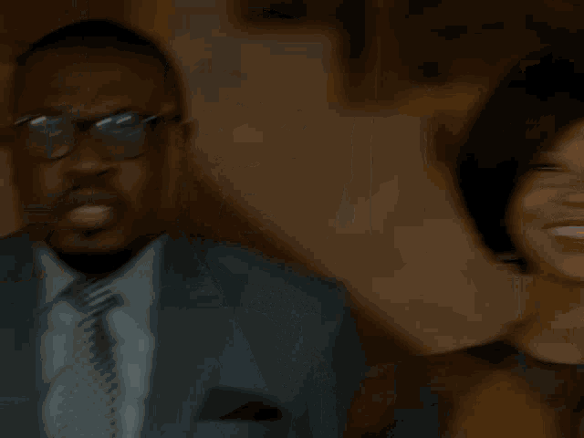 a man in a suit and tie touches his glasses