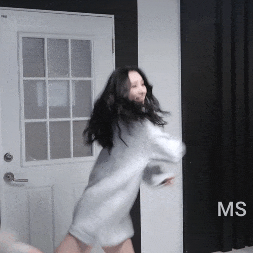 a woman in a white shirt is dancing in front of a door that says ms on it