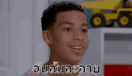 a young boy is smiling in a room with a toy truck behind him .