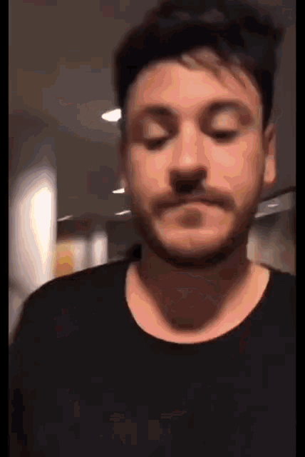 a man with a beard wearing a black shirt is making a funny face