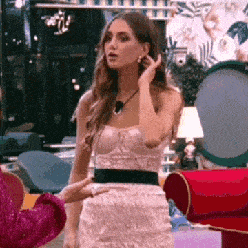 a woman in a pink dress is standing in a room with a red chair