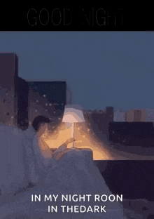 a man is sitting in bed reading a book while a lamp is lit .