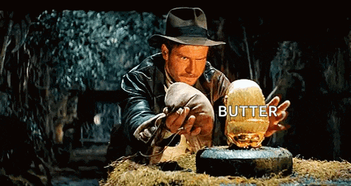 a man in a hat is holding a golden object that says butter on it