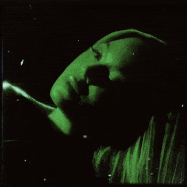 a woman 's face is glowing in green light
