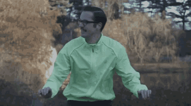 a man wearing glasses and a neon green jacket is dancing .
