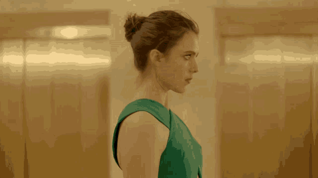 a woman in a green dress is looking over her shoulder at something