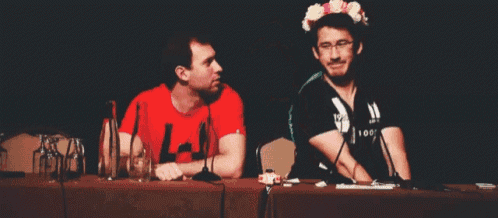 a man wearing a flower crown sits at a table