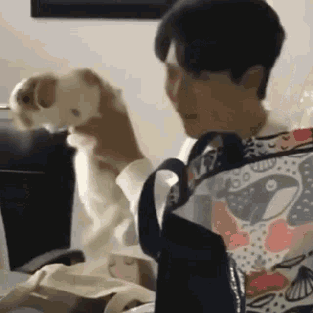 a man is holding a small dog in his arms while sitting at a desk .