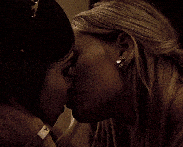 a woman wearing a silver wristband with the letter v on it kissing another woman