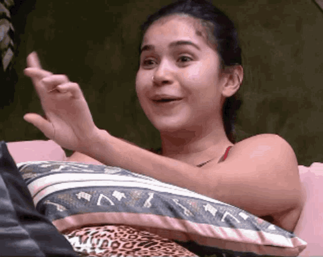 a woman is sitting on a couch with a pillow and making a face