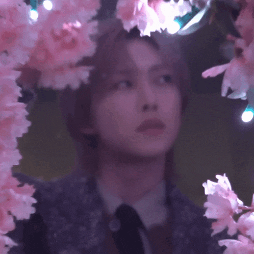 a man in a suit and tie is surrounded by pink flowers and lights
