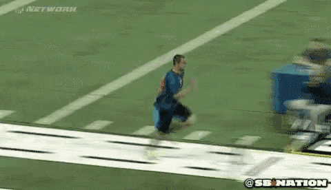 a man in a blue shirt is running on a football field with the sb nation logo in the background