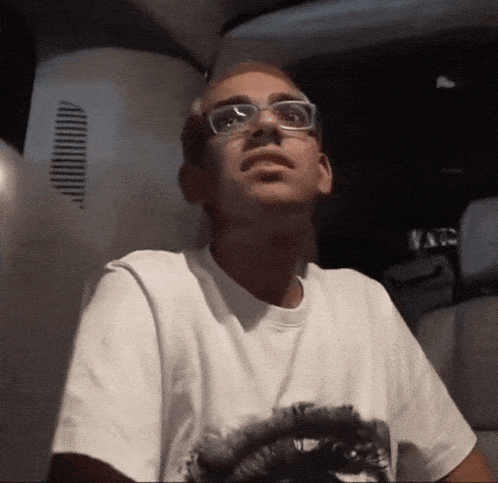 a man wearing glasses and a white t-shirt looks up