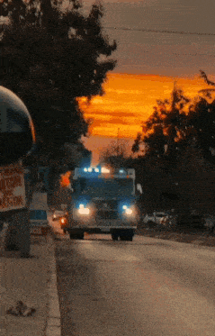 an ambulance is driving down a street with a sunset in the background and a sign that says " trafico motor "