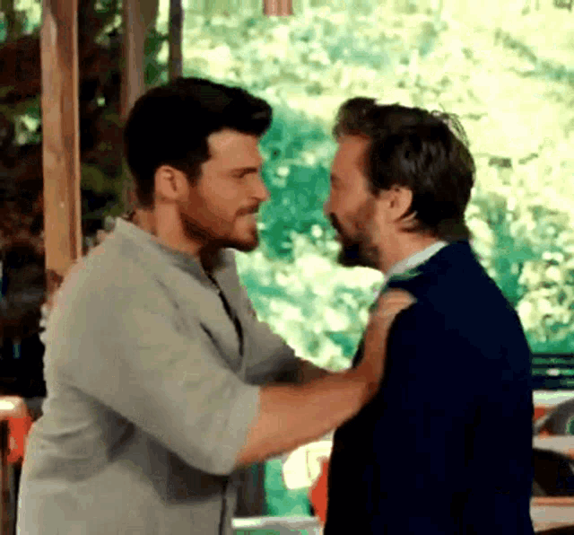 two men are standing next to each other and hugging .