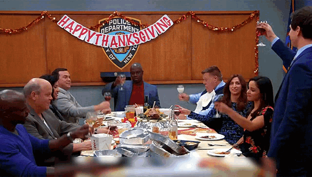 a group of people toasting at a table with a happy thanksgiving banner behind them